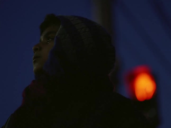 Child wearing winter gear stands at intersection at night