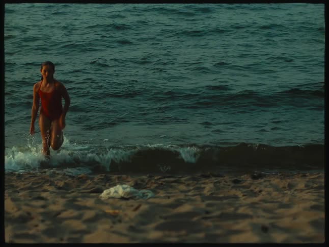 A little girl is running out of the water on a beach