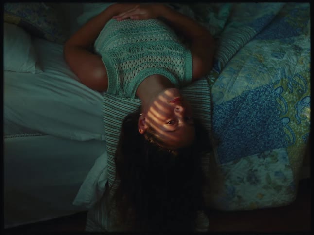 A woman is laying off the end of her bed