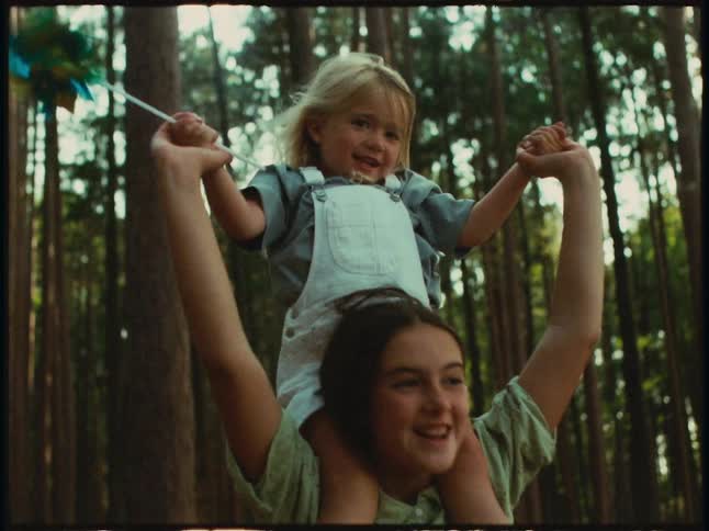 Girl carrying her little sister on their back in a forest