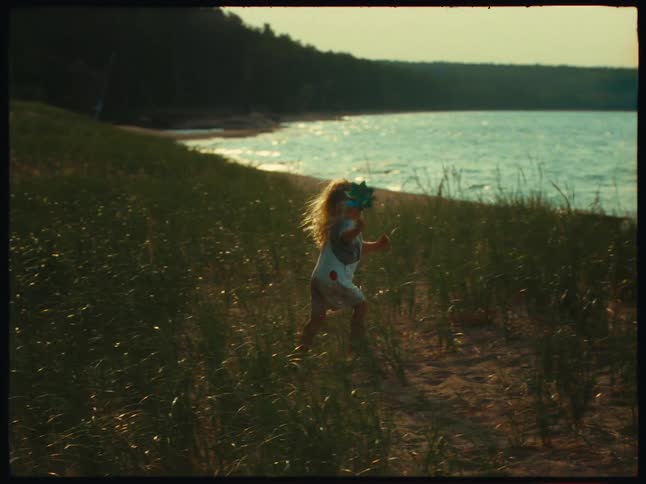 A little blonde girl walking in an area near the sea