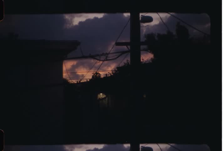 View of the silhouette of power poles amid residential houses on a day with a purple sky