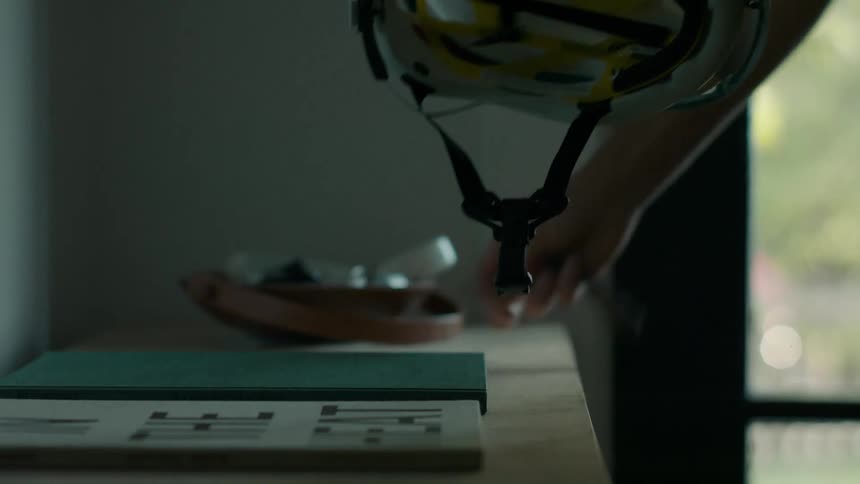 Human hands picking up a cycling helmet that is on a table