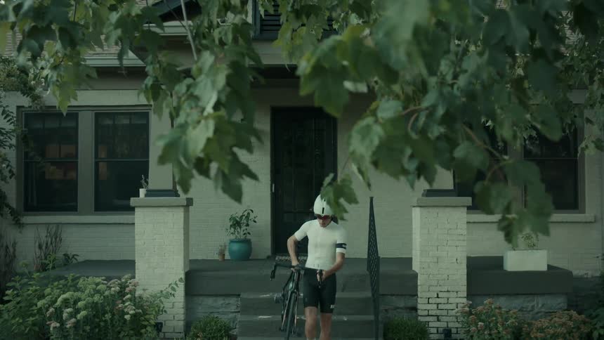 Man comes out of the house carrying a bicycle