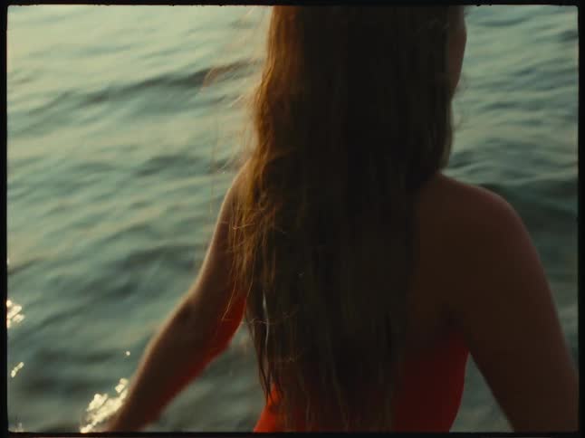 Girl in a red swimsuit dive in the ocean at evening