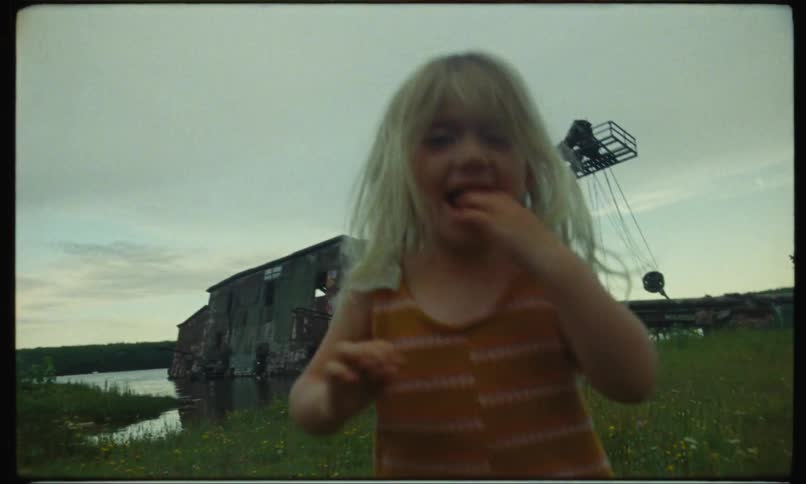 Toddler girl running on a grassy field smiling on a cloudy day