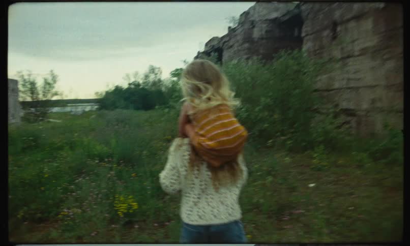 Girl runs on the countryside with her sister over her shoulders