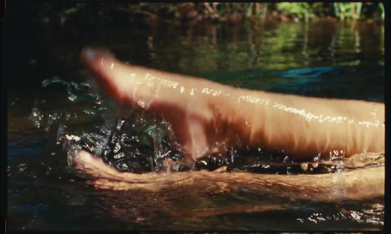 Girl splashes water in the lake with her feet