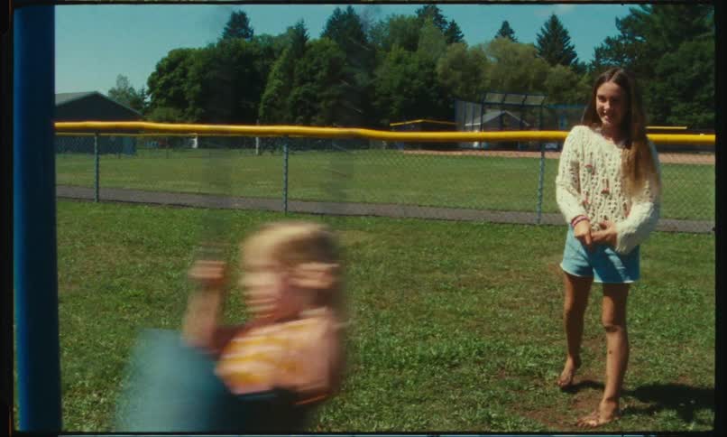 Girl playing with her sister on the swings in the park