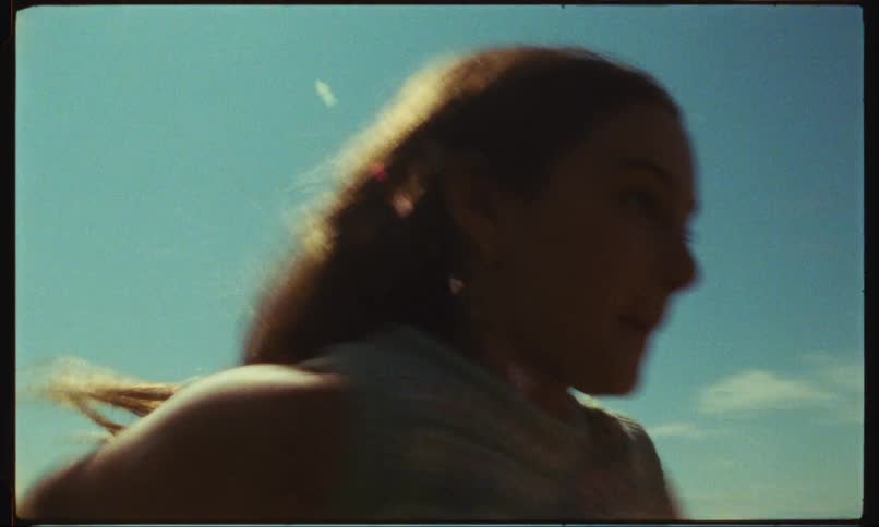 Girl smiles while running outdoors with forest in the background on a sunny day