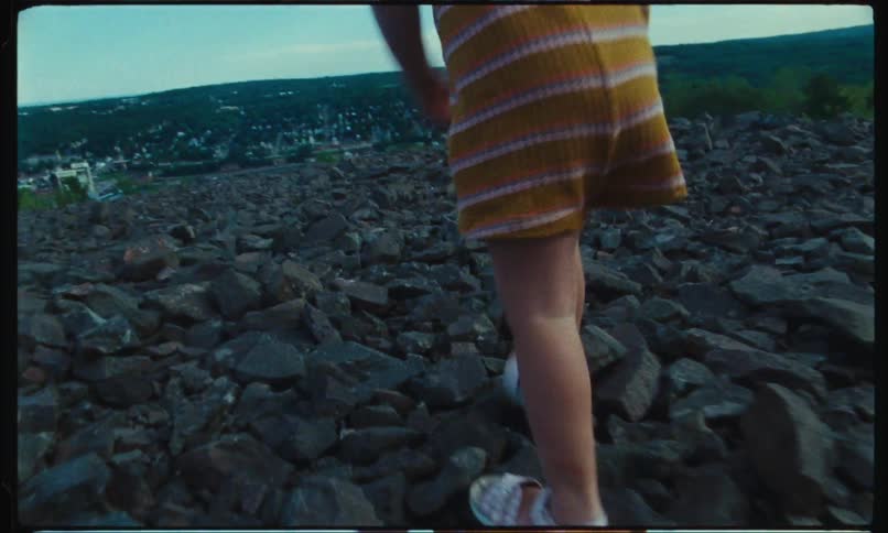Closeup of the legs of a blonde toddler walking among the rocks