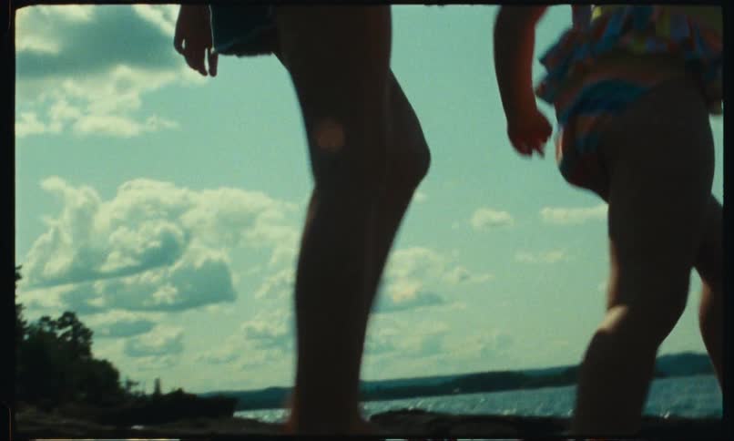 Closeup of the legs of a teenager and a child walking among the rocks by the seaside