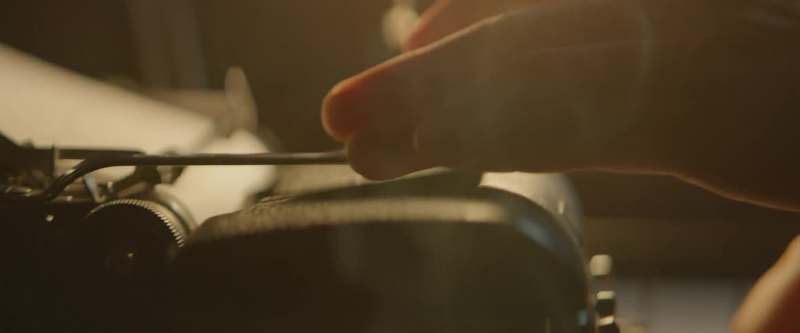 A person adjusts a typewriter in a smoky room