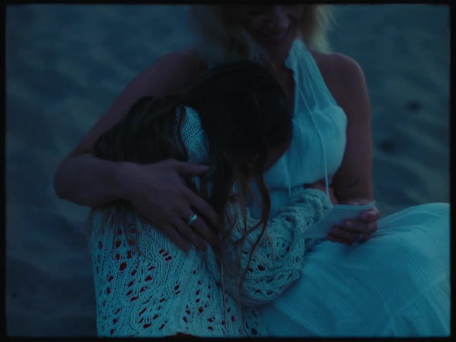 Happy mother and daughter sitting in the sand hug each other