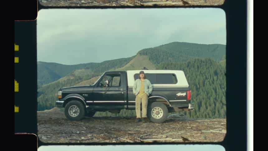 Man reclined on a pickup truck parked in the mountains