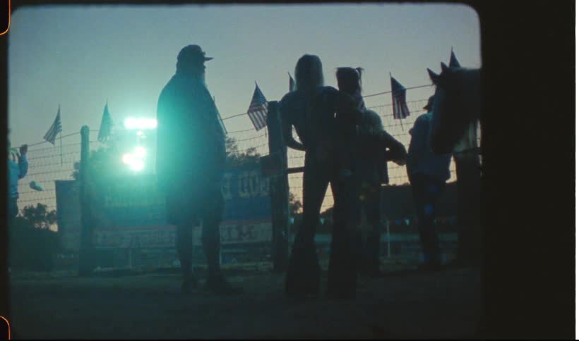 Family standing near a fence in a rodeo caught on vintage film