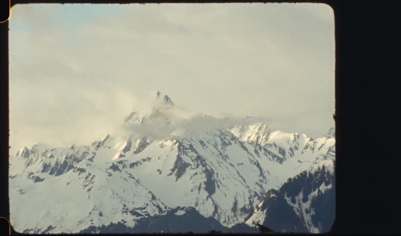 Snow covered mountain range peaking high in a cloudy sky