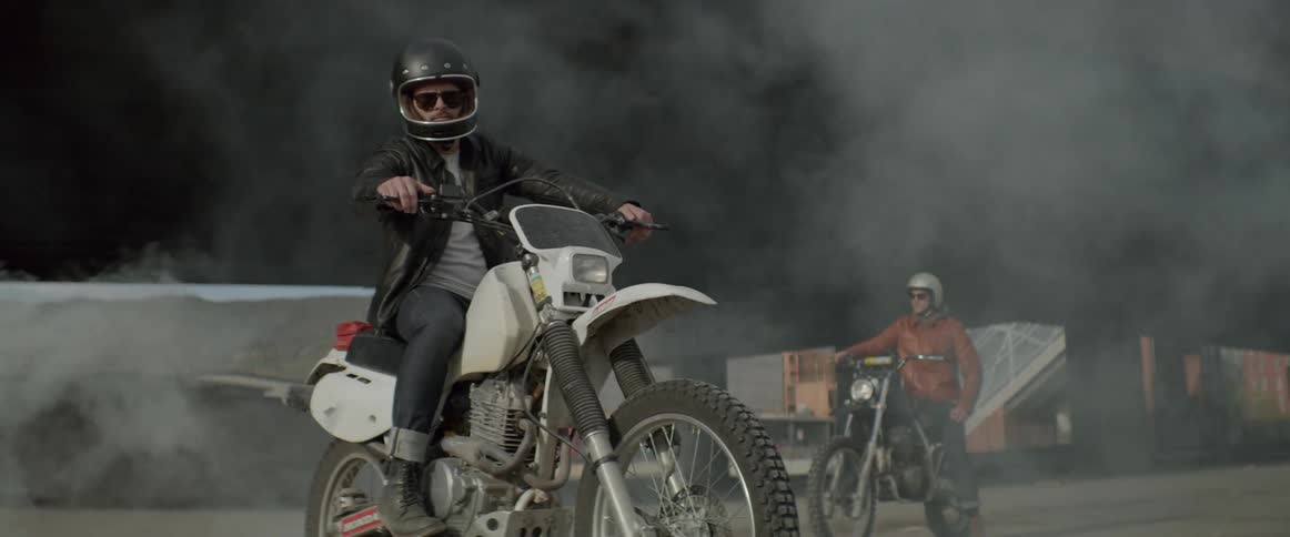 Two motorcyclists sitting on their dirt bikes under an overpass