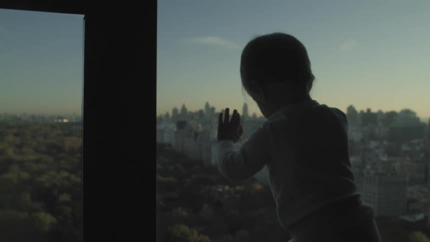 Girl looking at new york city at sunset from the apartment window