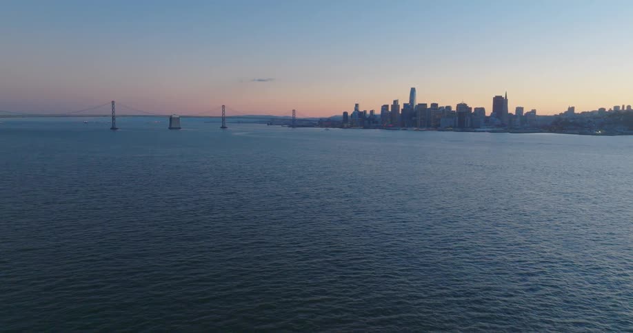 Aerial view of the skyline of a city with a suspension bridge at evening