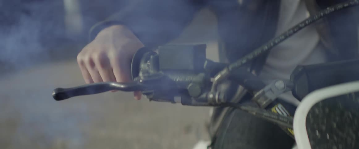 A man revs his motorcycle as smoke lifts around him
