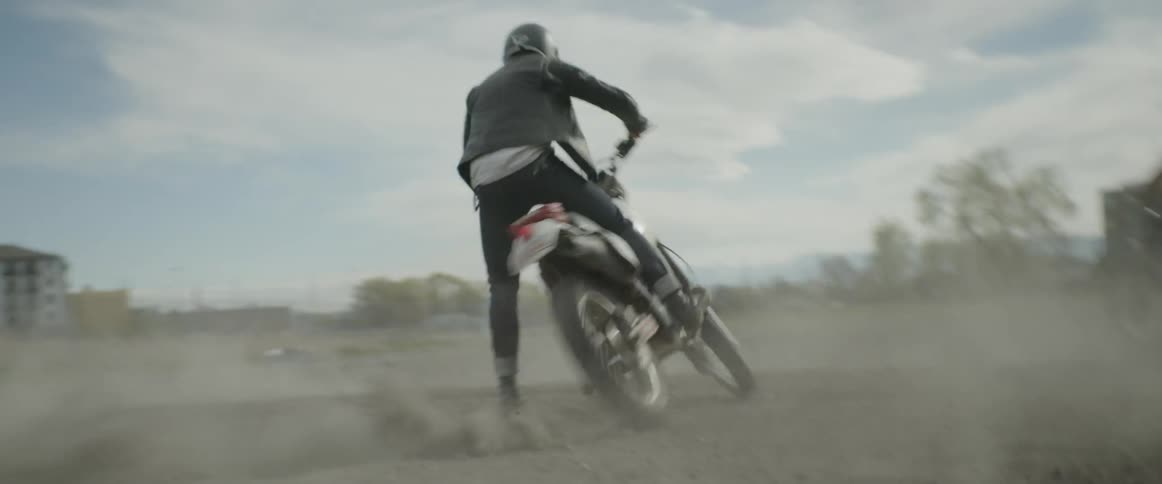A motorcyclist turns donuts  on a dirt and gravel surface