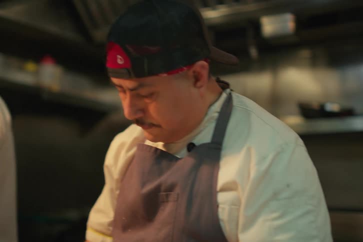 A busy kitchen scene with a chef cooking food at a restaurant kitchen