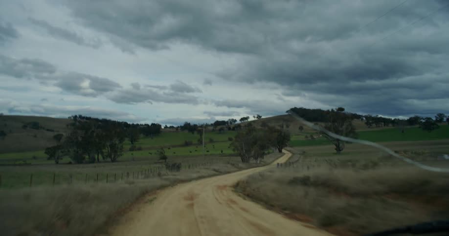 A vehicle driving down a dirt road on a grassy field