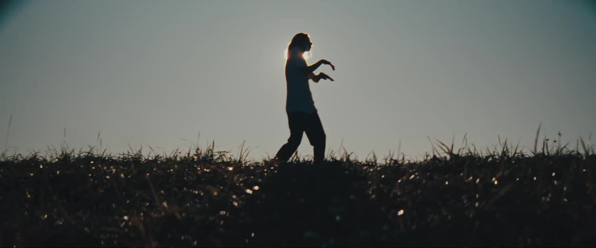 A person dancing in a grassland on a sunny day