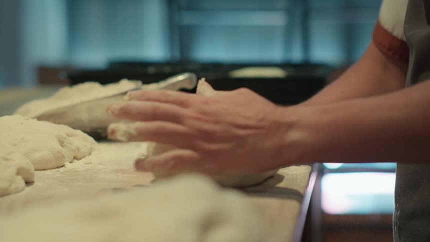 A pair of hands kneading and shaping bread dough