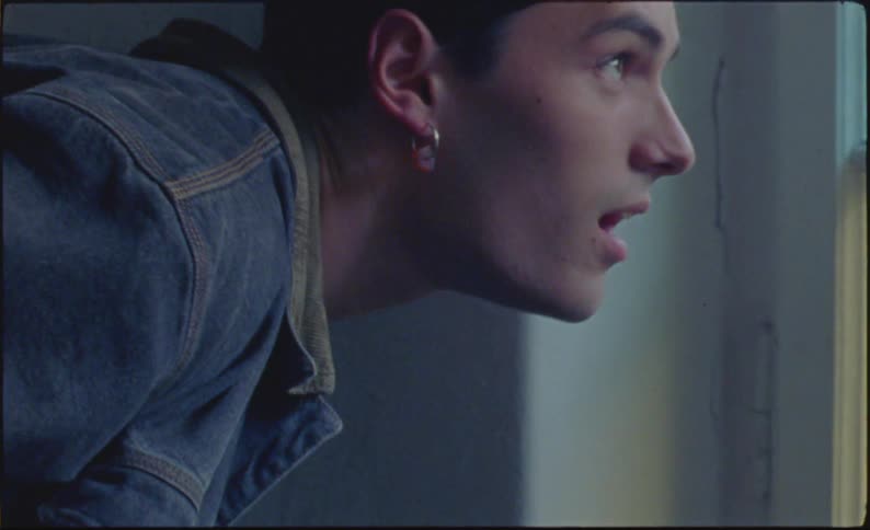 A young man is looking out a window while his mouth is open