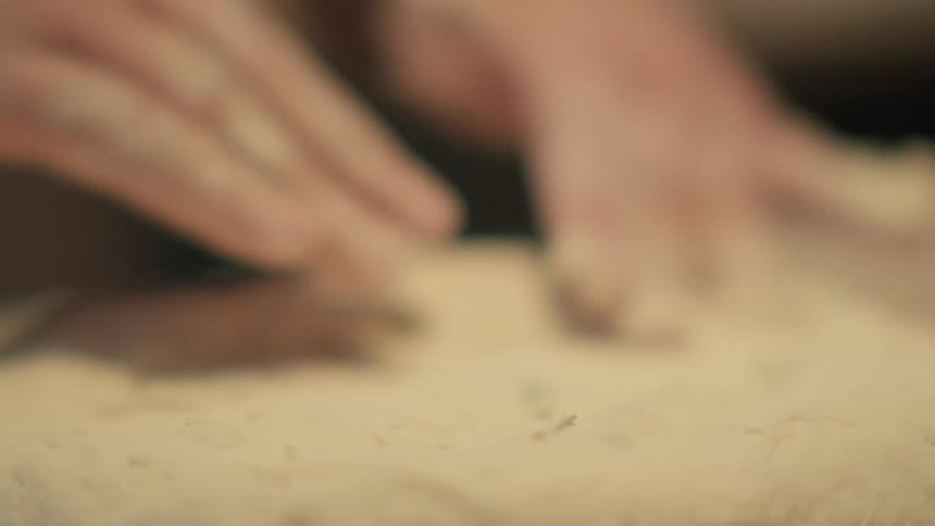 Close up of a person kneading dough over a table