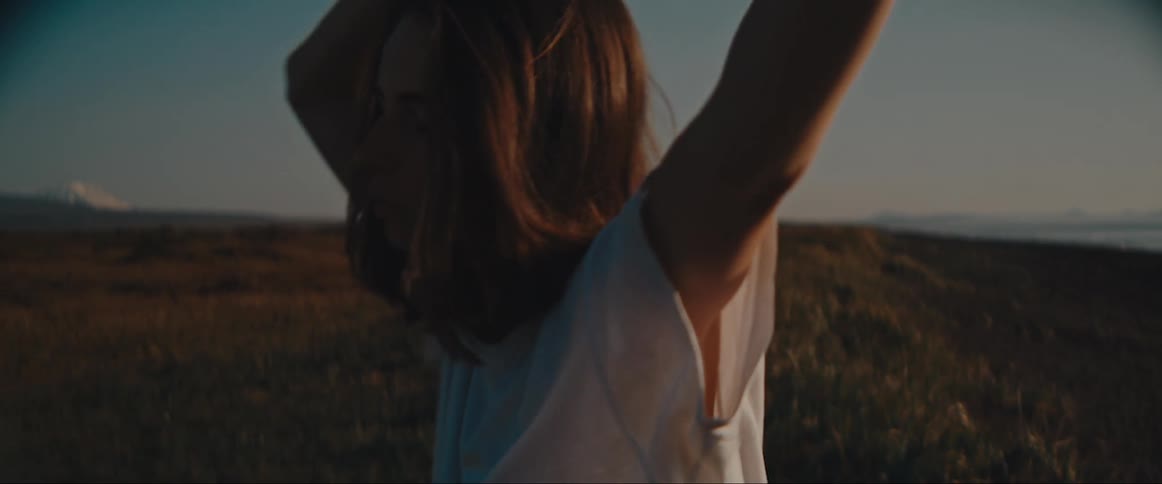 A serene scene of a person raising their arms in a field under a clear sky