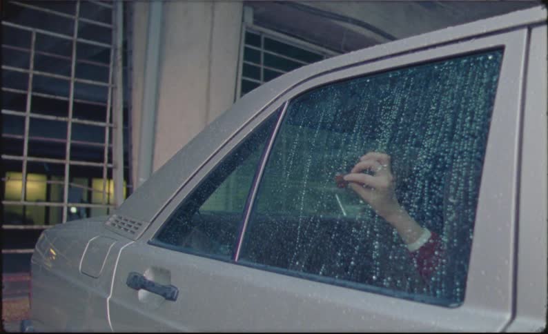 A woman looking sad while laying down in the backseat of a car