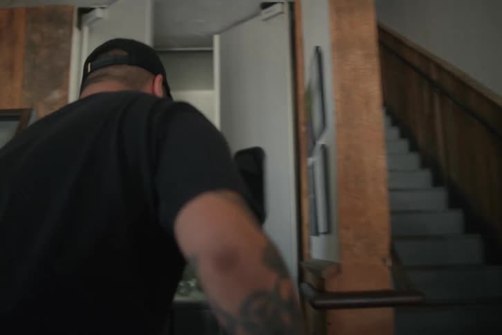 A man wearing a hat picked up a box and dropped it inside a kitchen