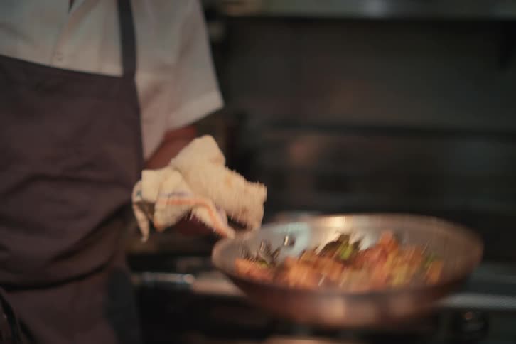 Chef tosses food on a pan in the restaurant kitchen