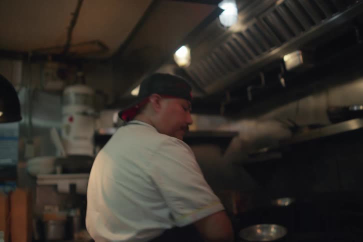 A busy kitchen scene with a chef cooking food at a restaurant kitchen