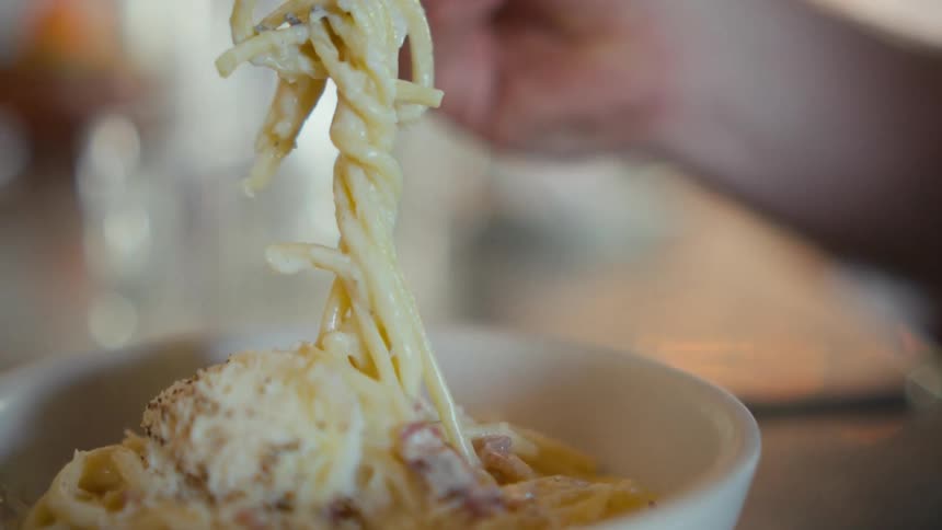 A person twirling pasta on a fork