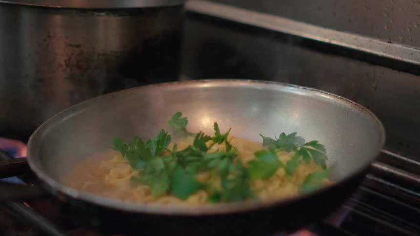 A pan cooking food and green leaves fall inside