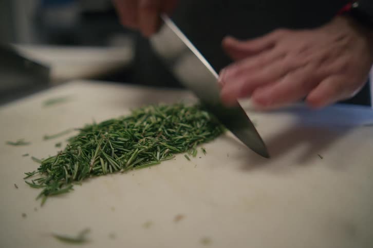 Close up of a chef chopping herbs with a sharp kitchen knife