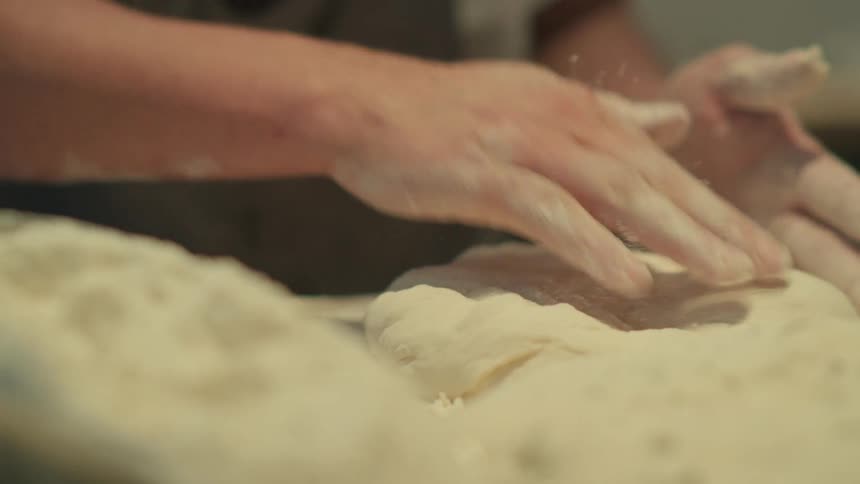 Close up of a person kneading dough over a table