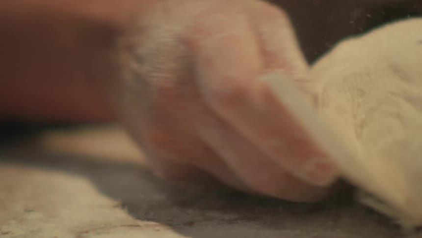 Close up of a person kneading dough over a table