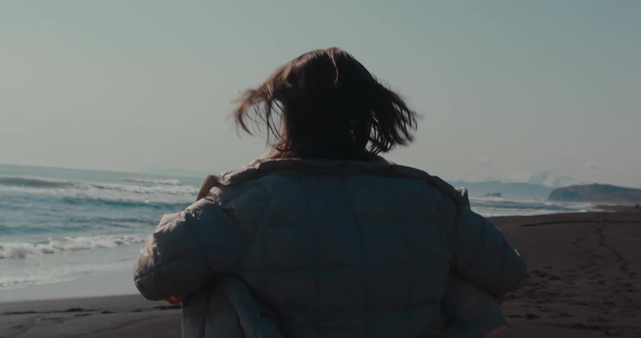 Happy woman wearing a coat prancing on the beach