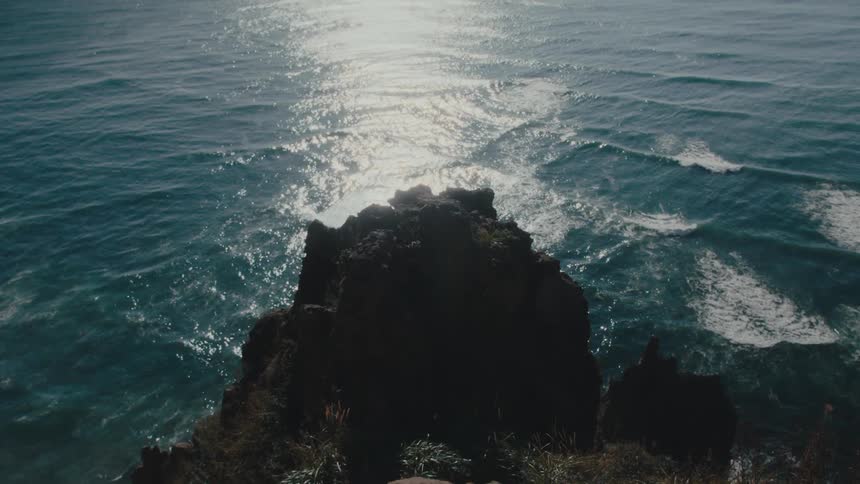 Gentle ocean waves around a rock promontory
