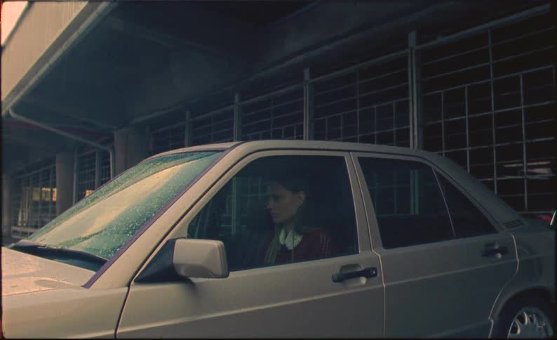 Sad woman sits in a parked car under the rain