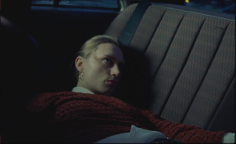 A lady resting on the backseat of a car at sunset
