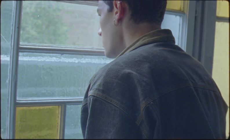 A man has his back turned and leans his head against the window glass