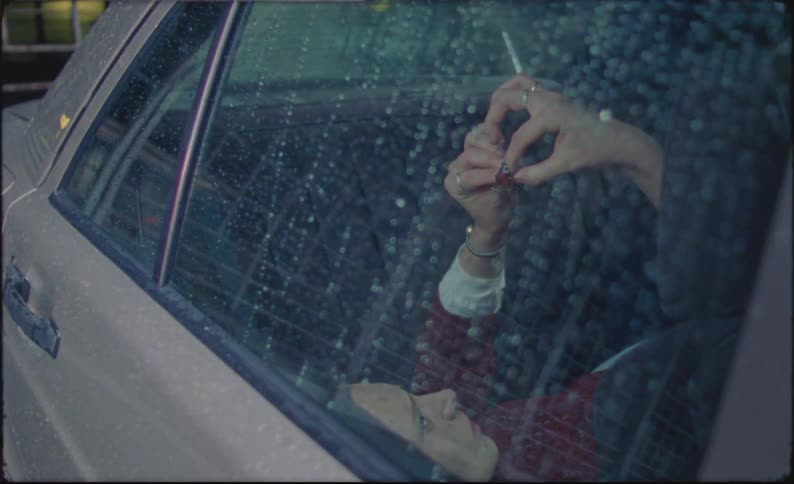 Woman resting in the backseat of a car in the rain