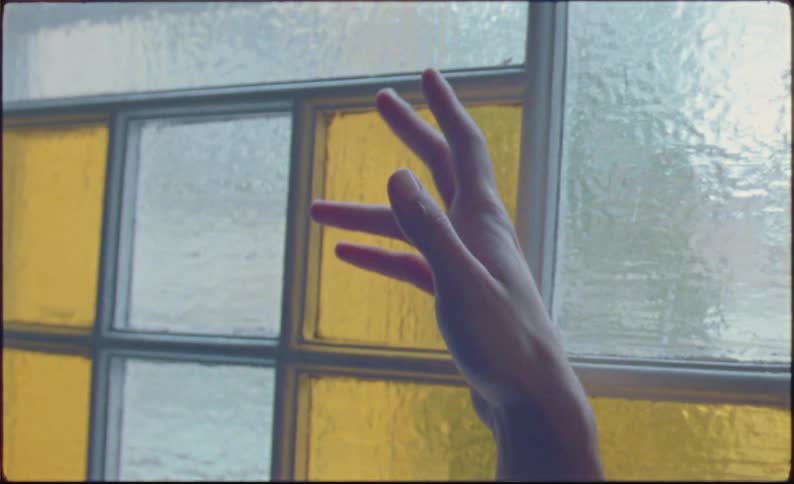 Man examines his hand as light from nearby stained glass plays across it