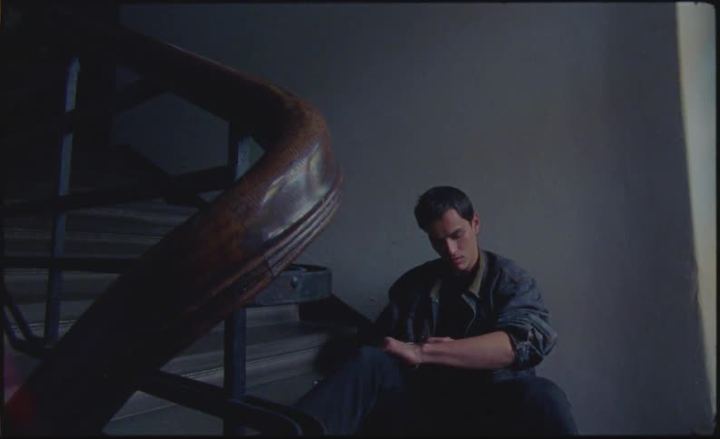 Young man sitting on a building staircase writing in his forearm